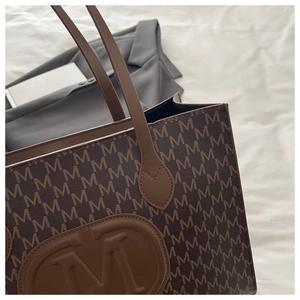 Détail du sac cabas marron café avec monogramme lettre M et écusson logo ovale gaufré
