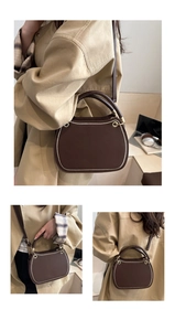 Detailed view of deep brown faux leather handbag with contrast stitching and gold hardware