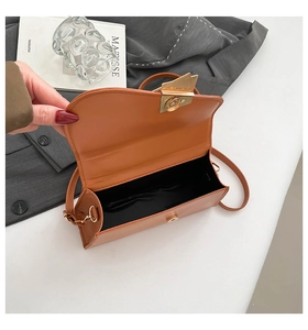 Close-up of orange leather handbag showing golden metal lock and black interior space