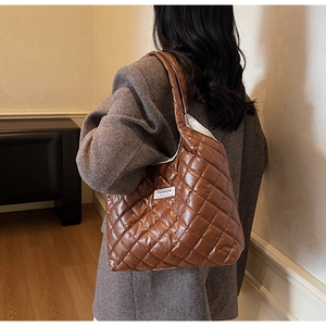 Close-up of brown quilted tote bag with glossy finish and fashion label detail