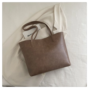 Detailed texture of brown faux leather tote bag on beige blazer and textured fabric