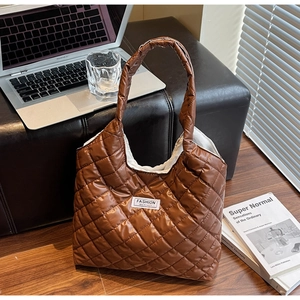 Brown quilted tote bag on wooden floor with office laptop and coffee cup background