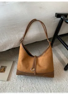 Detail of vintage brown suede tote bag with metal ring handle on beige rug
