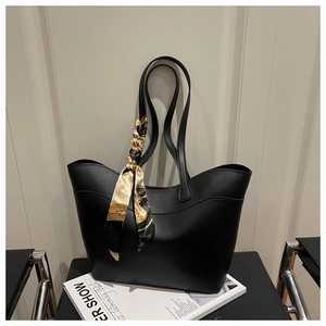 Close-up of black leather bucket bag featuring a decorative printed silk scarf on the handle