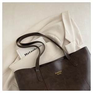 Detail of a large brown tote bag with retro leather texture and golden fashion lettering