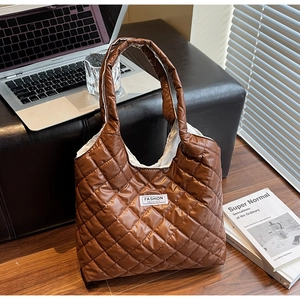 Close-up of a brown quilted tote bag with diamond pattern and white brand label