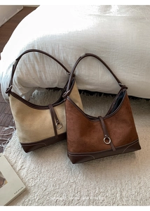 Detail of hobo shoulder bags in beige and brown suede with contrast stitching on carpet