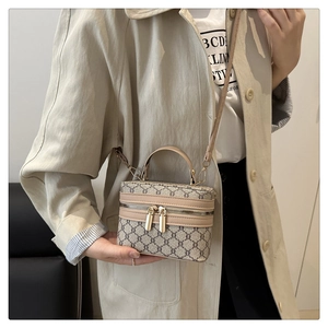 Detail of vintage geometric plaid pattern and gold hardware on box-style crossbody bag