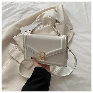 Detail of cream structured crossbody bag with elegant gold oval twist lock and PU leather texture
