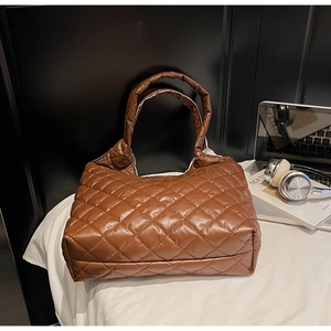 Detailed view of caramel quilted tote bag with diamond stitching on a modern display