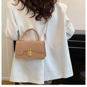Dettaglio borsa a mano beige in ecopelle con fibbia dorata e ciondolo alla moda
