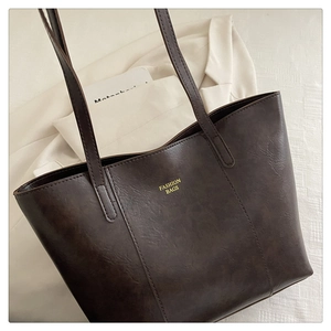 Detailed texture of dark brown PU leather tote bag with gold Fashion Bags lettering