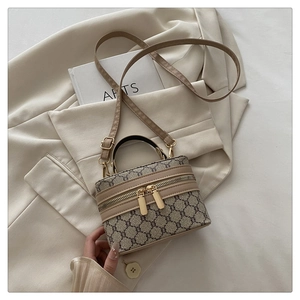 Close-up of vintage printed box bag with gold double zippers on a cream blazer