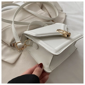 Detailed top view of white square crossbody bag with gold metal twist lock and top handle