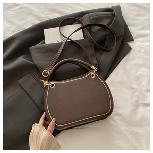 Detail of dark brown leather handbag with gold woven edges and adjustable shoulder strap