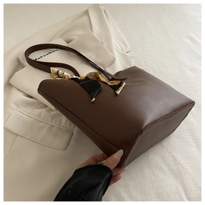 Detail of dark brown leather tote bag with stylish patterned scarf and long shoulder strap