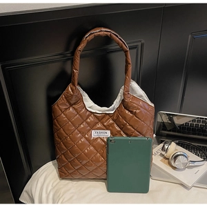 Detailed shot of brown quilted puffer tote bag featuring the Fashion Instinct woven label