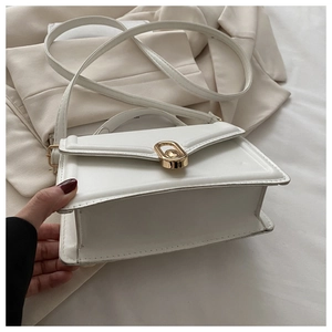 Close-up of a white square bag showing the golden oval metal buckle and neat stitching