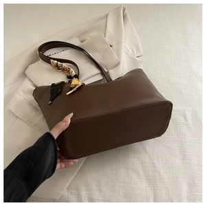 Detail of dark brown leather tote bag with decorative patterned scarf on handle