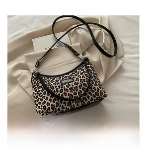 Detail of leopard print shoulder bag with black strap and fashion label on canvas fabric