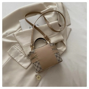 Detail of vintage monogram shoulder bag with brown leather trim on beige suit jacket