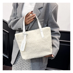 Close-up of white plush faux fur handbag with leather strap and embossed fashion tag