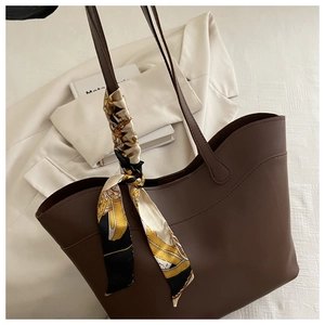 Close-up of brown tote bag featuring fine wavy stitching and decorative silk scarf handle