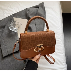 Detail of leopard print flap and golden ring rotary lock on brown leather crossbody bag