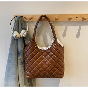 Detail of a brown quilted puffer shoulder bag with a glossy finish and rhombus pattern