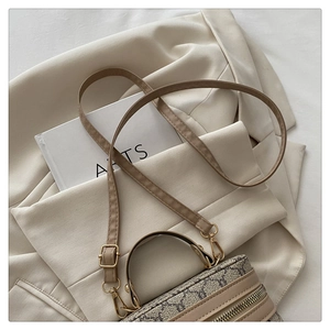 Detail of vintage monogram box bag with adjustable strap on cream blazer background