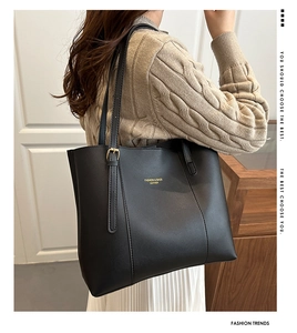 Close-up of black leather tote bag featuring gold embossed lettering and metal buckles
