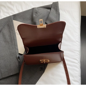 Detail of a brown leather crossbody bag featuring the iconic gold CD metal lock closure