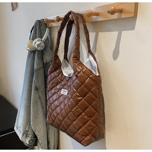 Detail of dark brown quilted tote bag with rhombus patterns and fashion label