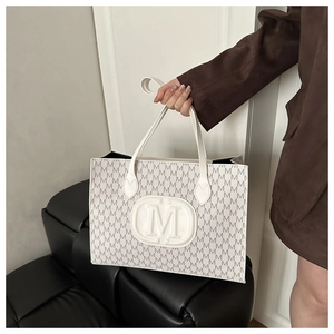 Detail of trendy tote bag with M-letter monogram print and embossed logo decoration