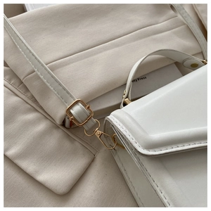 Detailed close-up of white leather square bag with gold hardware and fine stitching