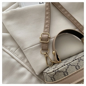 Close-up of golden hardware and vintage monogram pattern on stylish crossbody bag