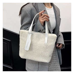 Detail of white plush tote bag showing soft faux fur texture and faux leather handles