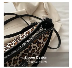 Close-up of durable silver metal zipper and brand tag on leopard print shoulder bag