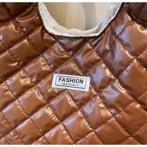 Close-up of brown quilted tote bag showing waterproof fabric and Fashion Instinct label