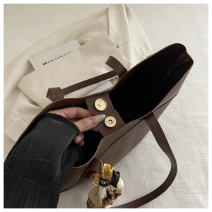Detail view of large brown tote bag with magnetic closure and floral silk scarf decor