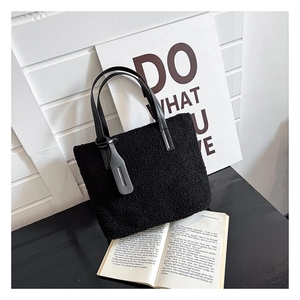 Close-up of black fleece tote bag with leather handles and fashion tag on wooden background