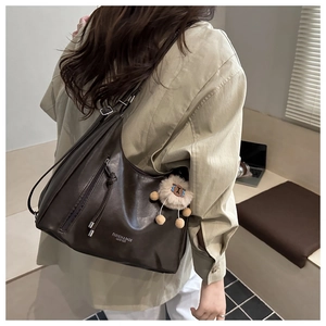 Detail of dark brown vintage faux leather shoulder bag with zipper and plush charm decoration