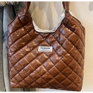 Close-up of brown quilted tote bag showing glossy nylon fabric and fashion logo label