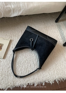 Detail of black hobo bag with suede and leather patchwork and white contrast stitching
