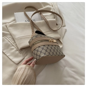 Close-up of vintage printed box bag with beige leather trim and gold zippers on books