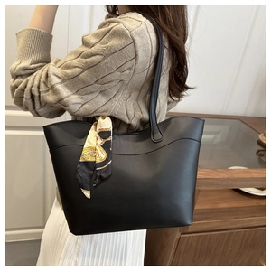 Detailed view of a black matte tote bag with an elegant printed silk scarf handle
