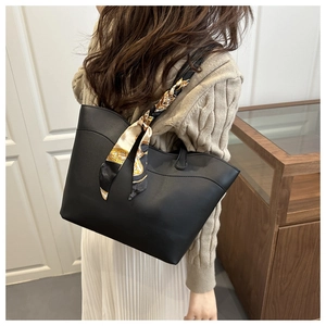 Detail of black tote bag with wavy edge design and decorative patterned silk scarf accessory