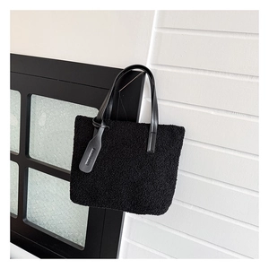Detail of black faux shearling bucket bag with leather handles and fashion design tag