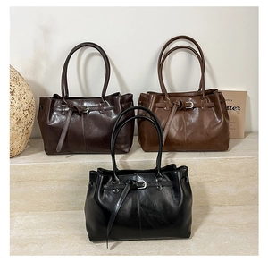 Detailed close-up of premium leather tote bags in black, coffee, and brown with metallic buckles
