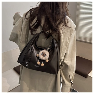 Dettaglio della borsa hobo in pelle marrone scuro con ciondolo a pecora e testo moda